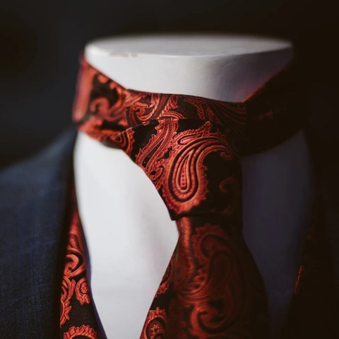A red paisley tie knotted on a white mannequin